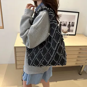 Sac cabas en jean noir matelassé avec détails effilochés porté par un mannequin