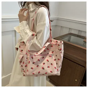Detail of pink corduroy tote bag featuring cute strawberry prints and front zipper pocket