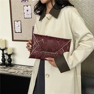 Deep burgundy envelope clutch with snakeskin embossing and golden metal trim detail