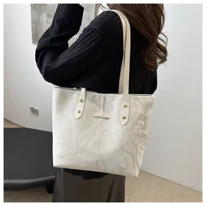 Detail view of the elegant marble pattern and gold metal accent on the white tote bag
