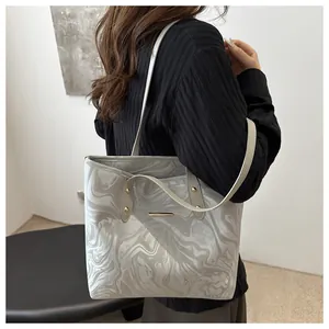 Detail of grey marble pattern tote bag with gold metal hardware and slim straps