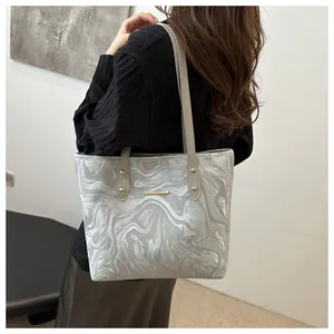 Detail view of silver marble ripple tote bag showing gold studs and slim shoulder straps