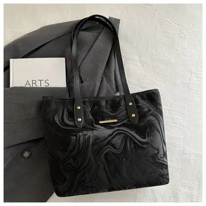 Close-up of black tote bag with marble pattern texture and golden hardware accents