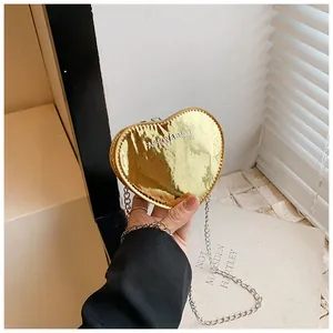 Macro detail of golden heart-shaped mini bag with metallic finish and silver chain strap