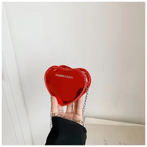 Close-up of mini heart-shaped crossbody bag in bright red patent leather with silver chain