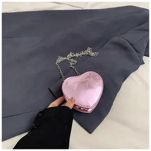 Detail of pink heart-shaped mini bag in glossy mirror leather with silver chain strap