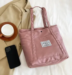 Vista superior de un bolso tote de nailon rosa empolvado con bolsillo exterior en fondo blanco