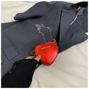 Detail of red heart-shaped patent leather mini bag with silver chain strap and logo