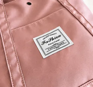 Primer plano de tela de nailon rosa con etiqueta tejida blanca y costuras reforzadas