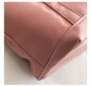 Detalle de costuras de alta precisión en tela de nailon rosa para bolso de hombro