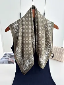Detail of olive green silk scarf featuring retro geometric patterns and white floral prints