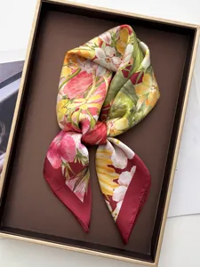 Detail of vibrant floral satin scarf with hand-rolled edges on a luxury display tray