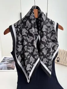 Detail view of black paisley print silk satin scarf with elegant white patterns