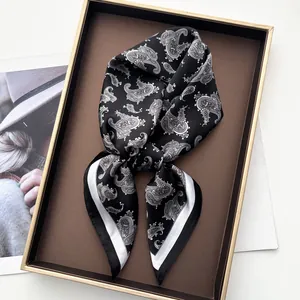 Detail of folded paisley silk square scarf with white stripe border on display tray