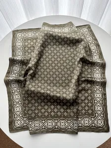 Close-up of olive green silk scarf featuring white geometric diamond patterns and drapes