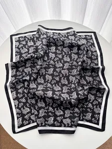 Detailed macro view of vintage black and white paisley silk scarf on a white table
