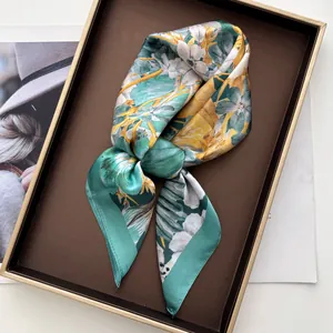 Detail of elegant floral silk scarf in mint green and ivory on a decorative display tray
