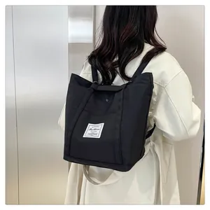 Vista detallada de la mochila negra de nailon multiusos llevada por una modelo real
