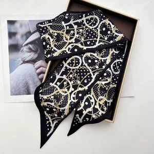 Detail of silk-feel skinny scarf with white polka dots and gold chain pattern on gift box