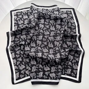 Close-up of black and white paisley silk scarf with satin luster and striped borders