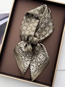 Detailed macro view of olive green silk scarf with geometric pattern in a gold-rimmed box