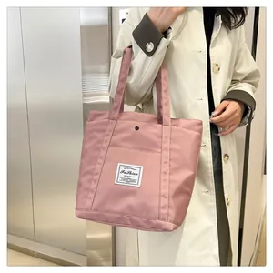 Detalle de bolso tote de nailon rosa con etiqueta de moda y botón de presión metálico