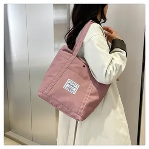 Detalle del bolso tote de nailon rosa con etiqueta tejida blanca y hebilla lateral metálica