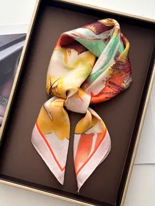 Macro shot of abstract oil painting floral silk scarf tied in elegant bow on tray