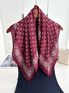 Detail of vintage geometric flower print silk scarf draped on a wooden hanger