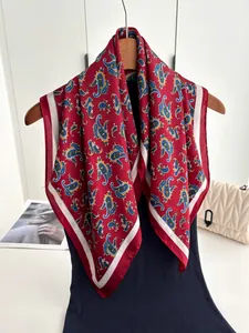 Detail of red paisley silk square scarf with blue patterns hanging on a wooden hanger
