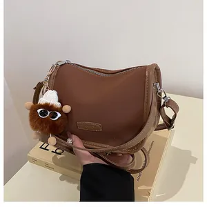 Dettaglio borsa a tracolla marrone retrò con ciondolo in peluche e etichetta di moda