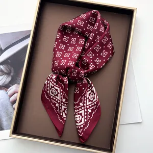 Detail of burgundy silk scarf with white geometric patterns in a brown gift box