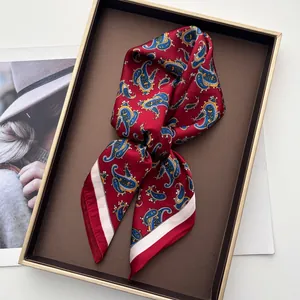 Macro detail of dark red paisley silk scarf with satin finish in a gift box display