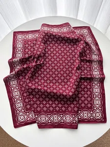 Detailed view of wine red silk scarf with intricate white ethnic geometric patterns