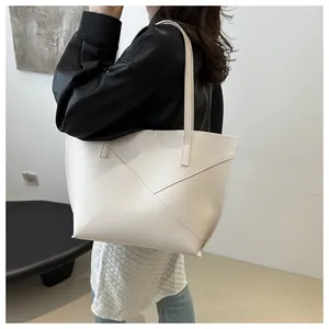 Dettaglio borsa tote bianca con cuciture geometriche indossata da una modella