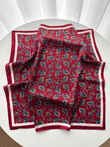 Detailed view of red paisley patterned silk scarf with premium glossy texture and soft drapes