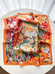 Detailed view of floral silk scarf with realistic daisy and lily prints on orange satin