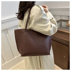 Dettaglio della borsa tote bordeaux con cuciture geometriche indossata a spalla