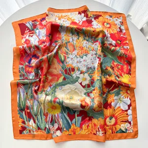 Detailed close-up of a square silk scarf with floral sunflower print and orange borders