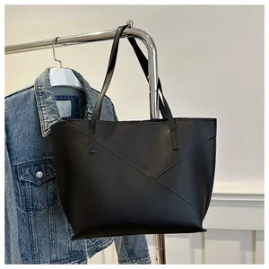 Dettaglio della borsa tote nera con patchwork geometrico asimmetrico e spalline lunghe