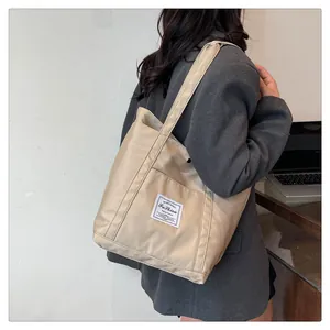 Detalle del bolso tote de nailon caqui con bolsillo frontal y cremallera funcional
