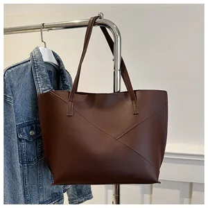Dettaglio della borsa tote marrone scuro con cuciture geometriche e finitura opaca