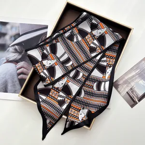 Detail of silk twilly scarf with horse and chain patterns in a luxury gold gift box