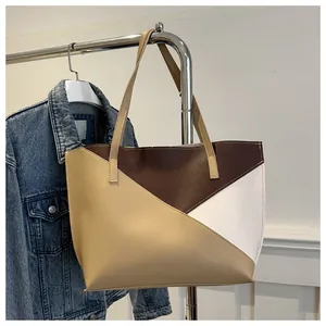 Dettaglio della borsa tote patchwork a colori appesa a un supporto metallico moderno