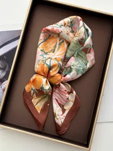 Detailed view of floral satin scarf with brown borders folded elegantly in a tray