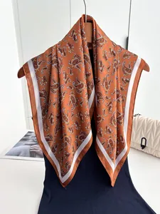 Close-up of vintage paisley pattern silk scarf with orange tones hanging on a hanger