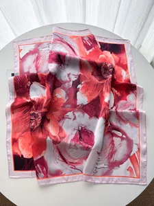 Macro shot of large floral pattern silk scarf on white table with soft lighting