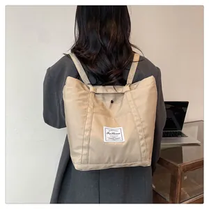 Vista trasera de modelo con un bolso maternal de nailon beige como mochila de moda