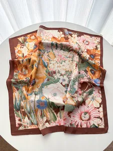 Detail view of large silk scarf featuring elegant botanical patterns and a brown border