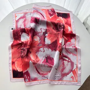 Detailed view of floral silk scarf featuring vibrant red abstract petals and pink rolled edges